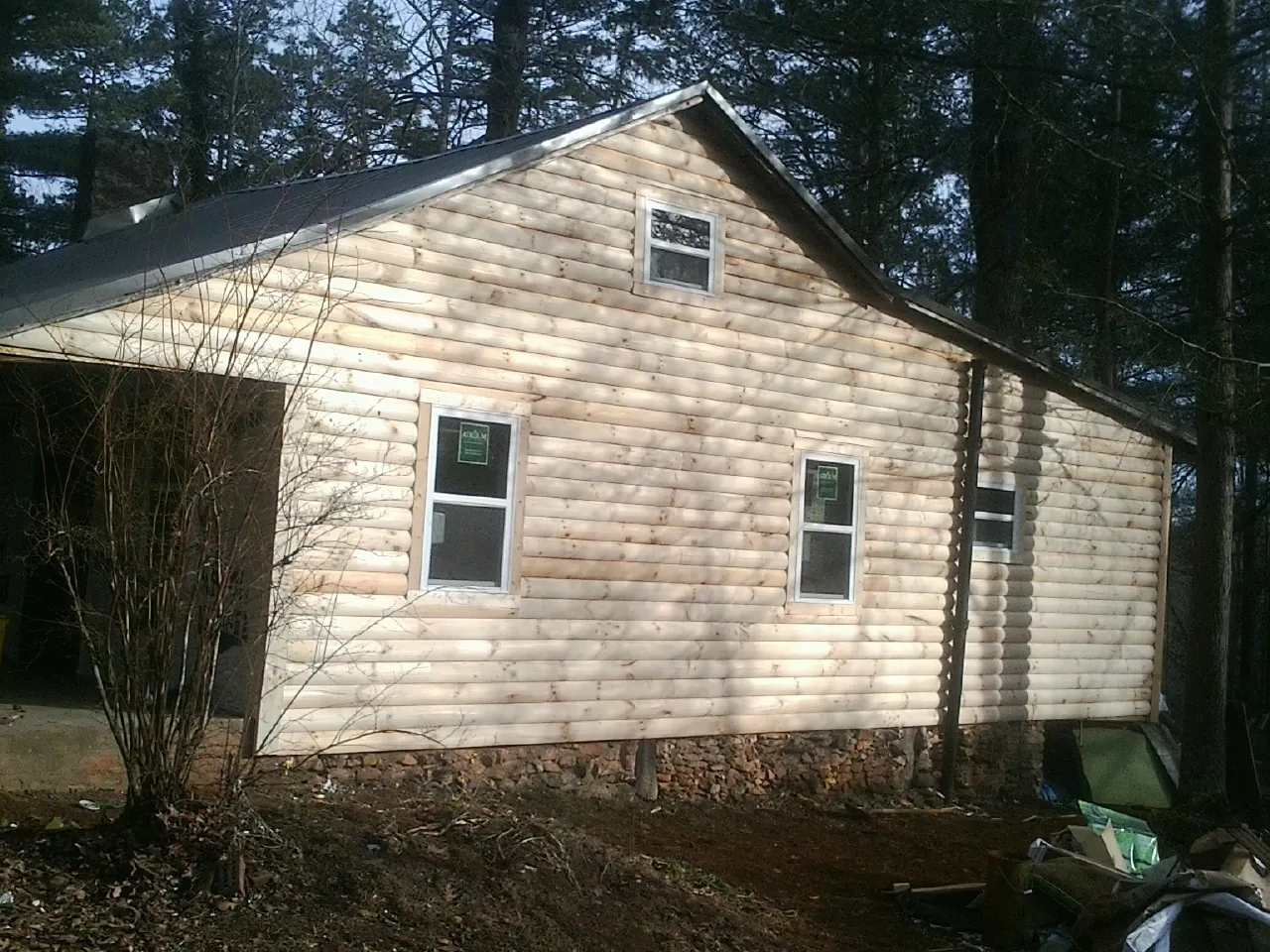 New log siding and dark metal roofing on a gable end in Ogunquit