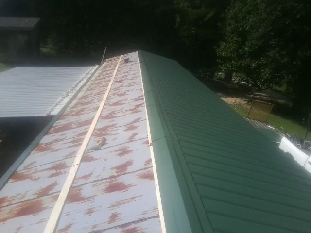 Old rusted panels beside newly installed green metal roofing — Wind Damage Roof Repair by Roofing Brothers in Ogunquit