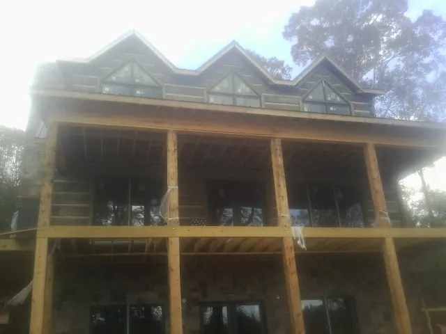 Dormers and porch framing on a large log home under construction — Roof Coating work by our crew in Ogunquit