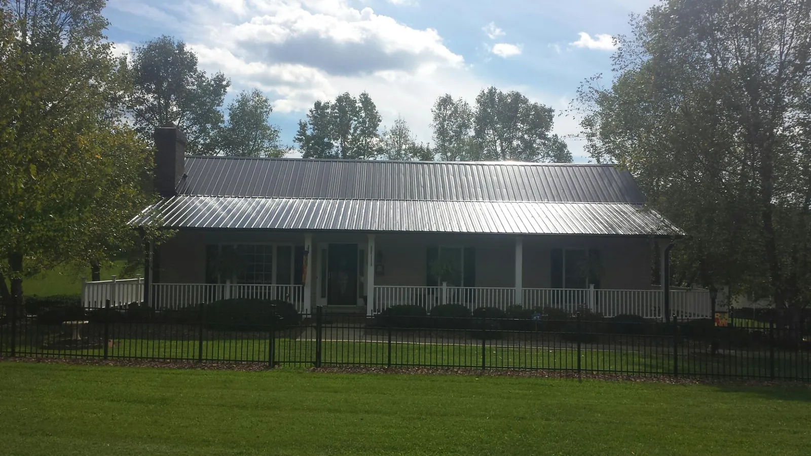 Gray metal roof on a brick ranch with a full width front porch — Gutter Guard Installation work by our crew in Ogunquit