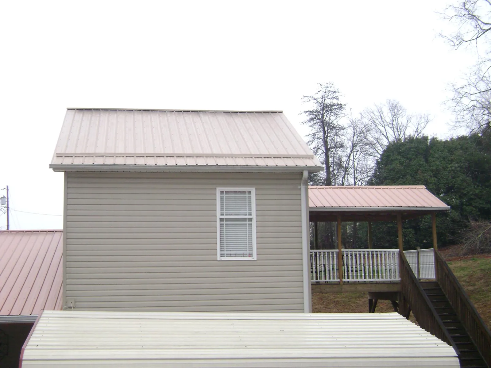 Tan metal roofs on a two story addition and attached porch, from a Roof Replacement job in Ogunquit